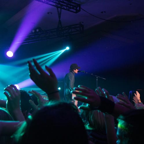 Musician playing guitar under dramatic stage lighting in a club setting.